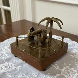 Vintage brass cannon with palm tree and chain fence